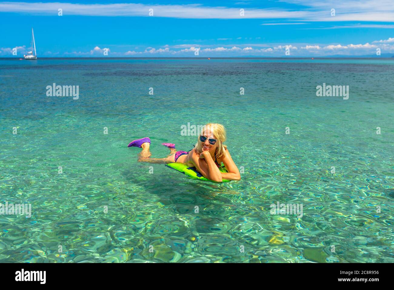 Bikini blonde fille dans les eaux cristallines de la mer, bains de soleil  sur un matelas de plage à Prunini plage o Seccione Plage de l'île d'Elbe en  Italie. Mer Tyrrhénienne Photo