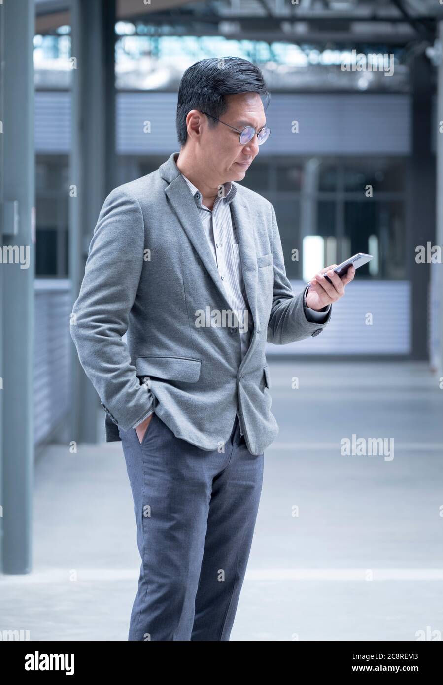 Homme d'affaires chinois avec veste en regardant son téléphone portable dans la main Banque D'Images