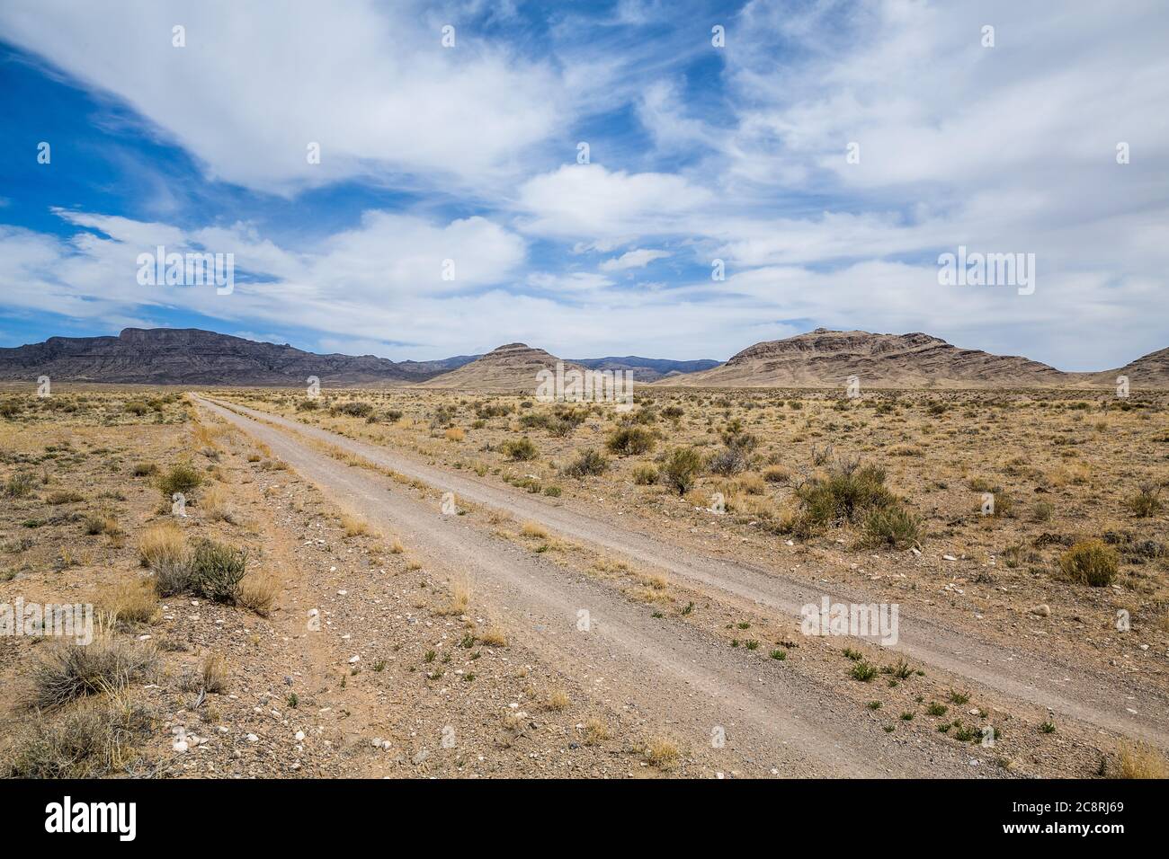 Petites falaises et formations rocheuses du désert ouest de l'Utah. La direction vers une montagne lointaine est une petite piste de terre à travers le sagebrush. Banque D'Images