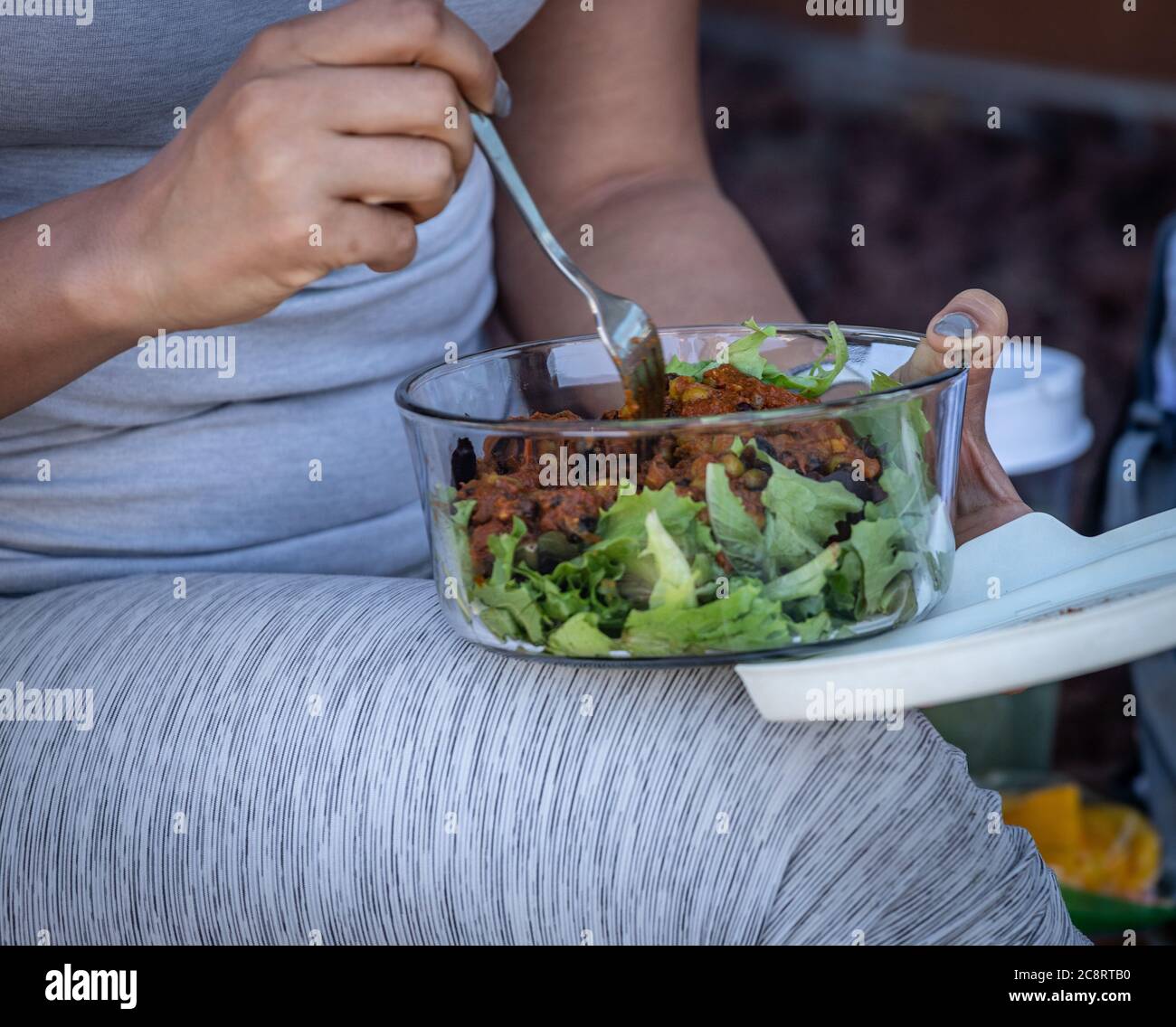 Jeune femme mangeant un contenant transparent avec une salade saine Banque D'Images