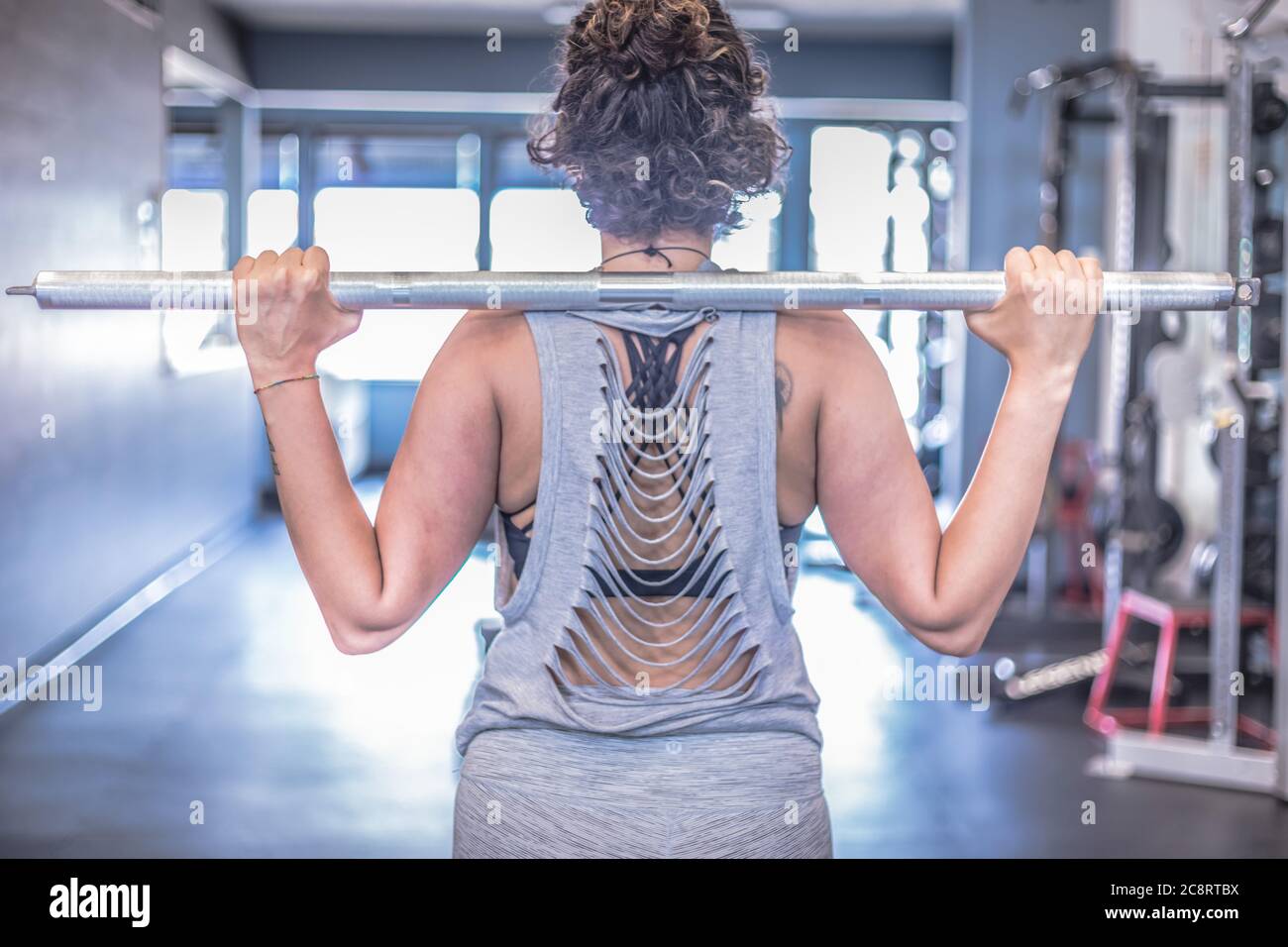 vue arrière d'une athlète féminine tenant une barre de poids sur ses épaules Banque D'Images