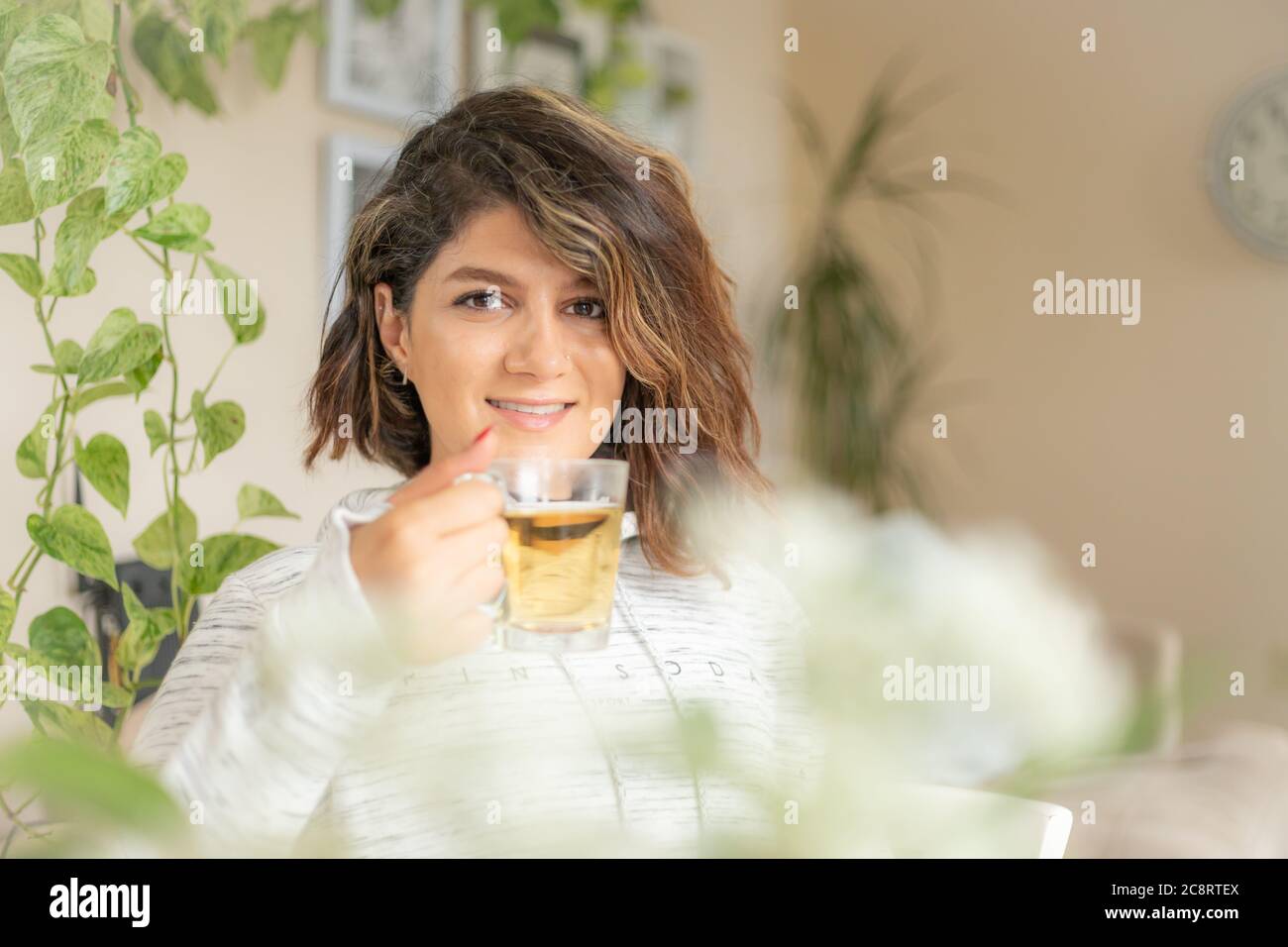 Jeune femme regardant l'appareil photo dans sa maison Banque D'Images