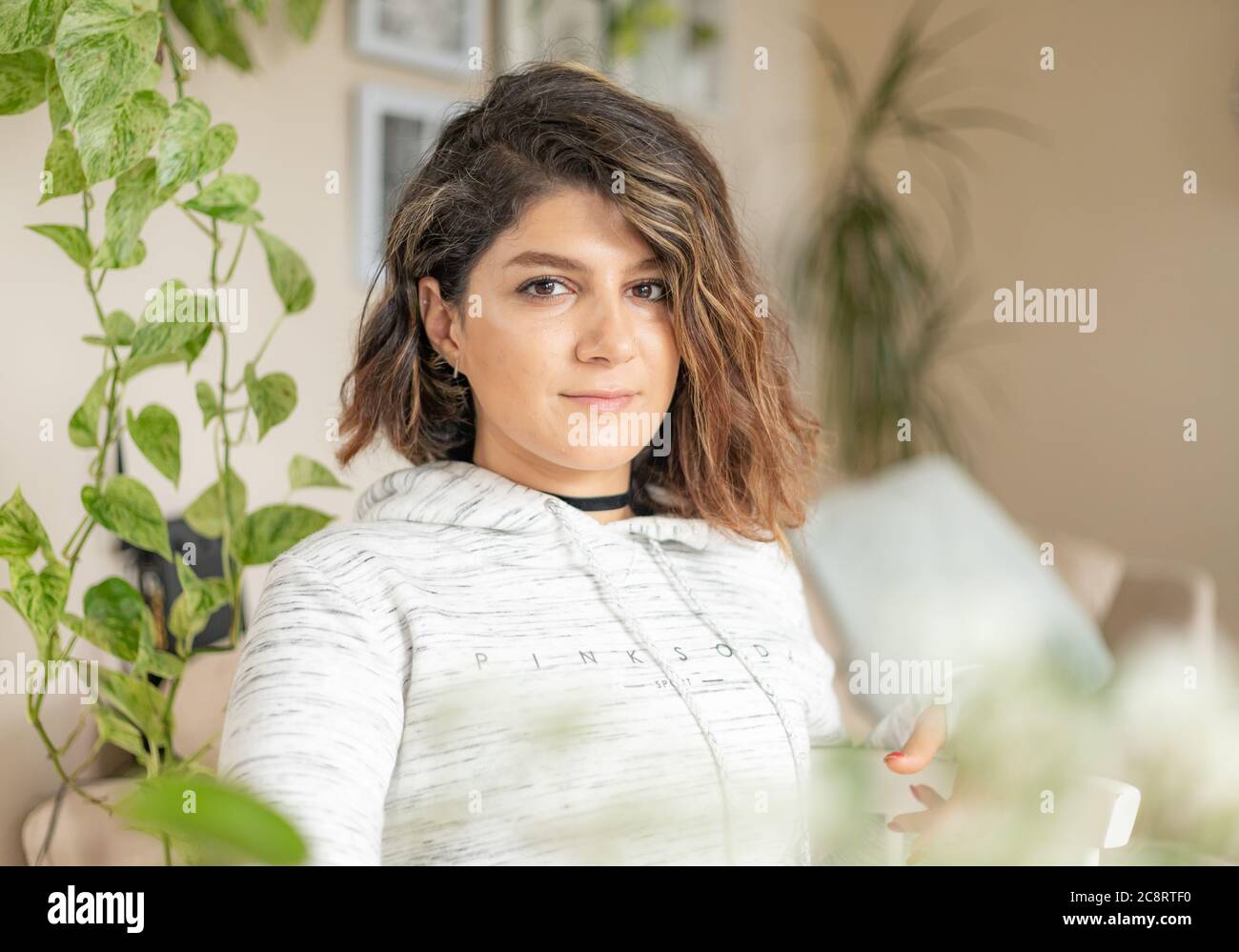 Jeune femme regardant l'appareil photo dans sa maison Banque D'Images