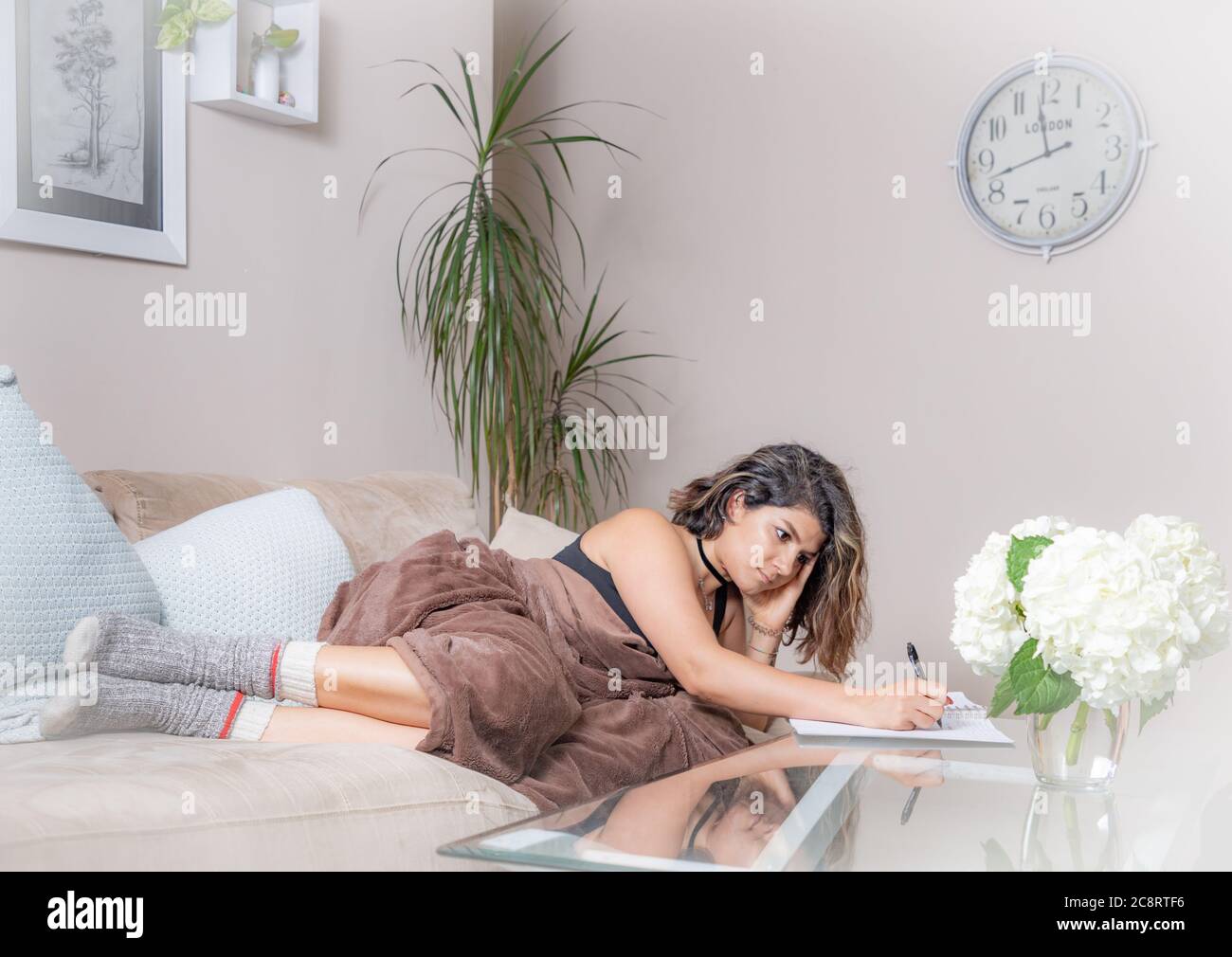 Une jeune femme sur un canapé écrivant dans un journal Banque D'Images