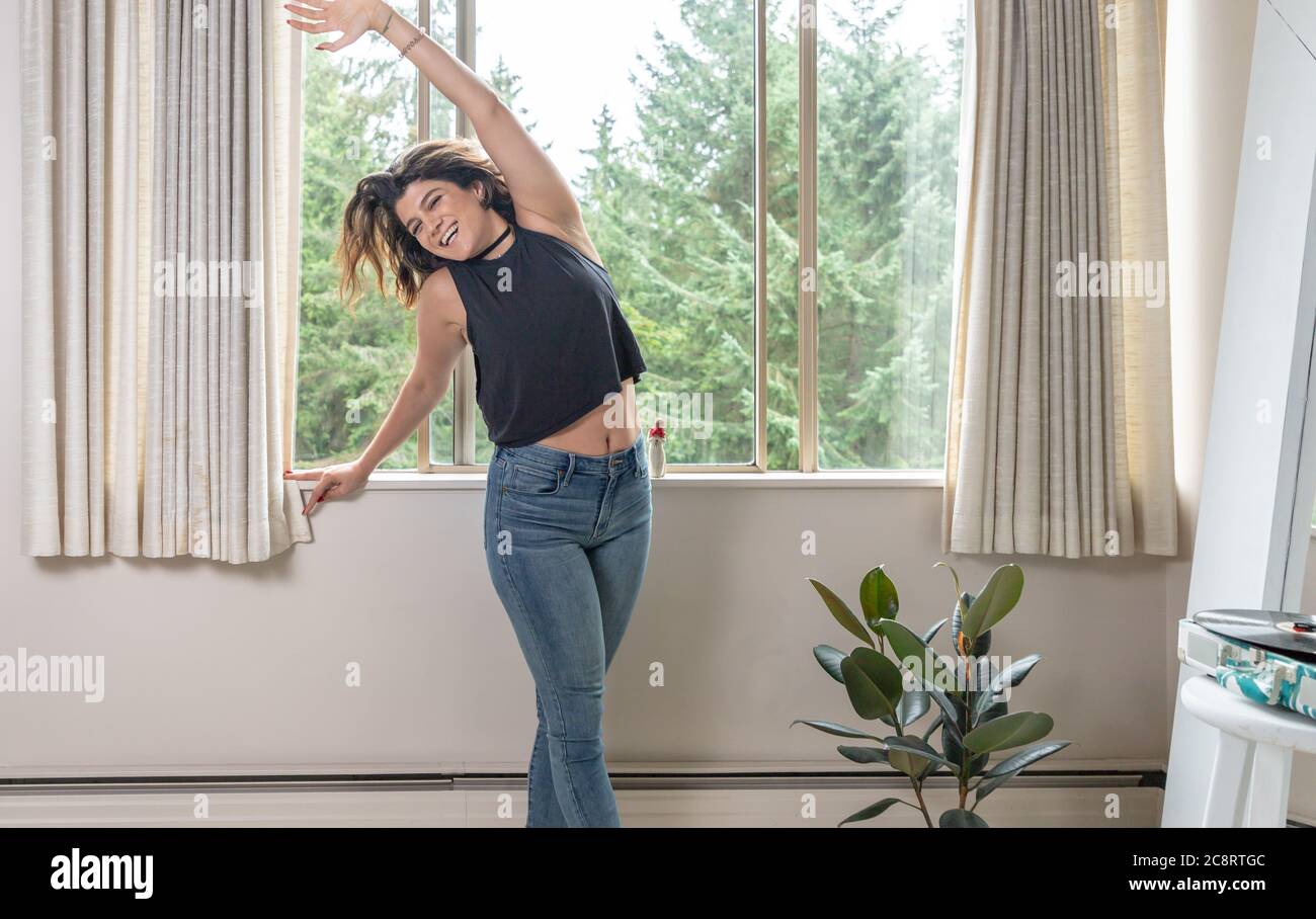 Jeune femme s'étendant à la musique sur un lecteur de disques Banque D'Images