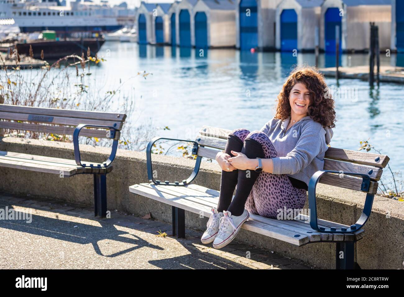 Jeune femme sur le banc à côté de la marina Banque D'Images