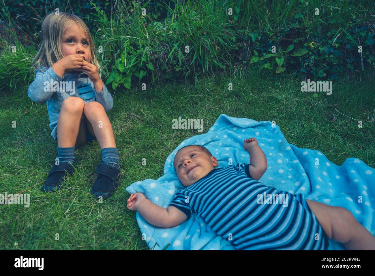 Un enfant de la chambre est assis sur la pelouse avec sa petite sœur Banque D'Images