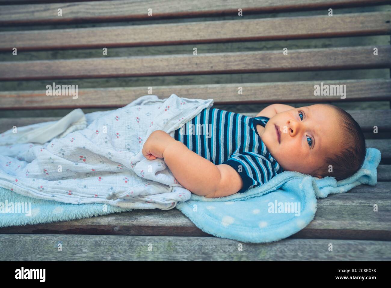Un petit bébé repose sur un banc Banque D'Images