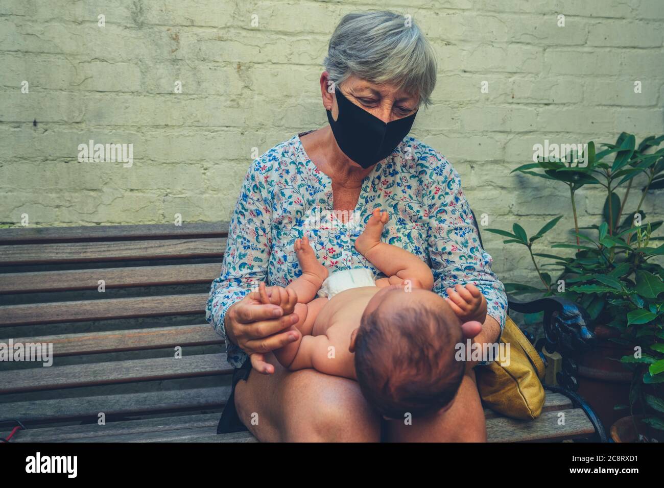 Photo authentique de grand-mère avec un masque facial tenant son petit-enfant Banque D'Images