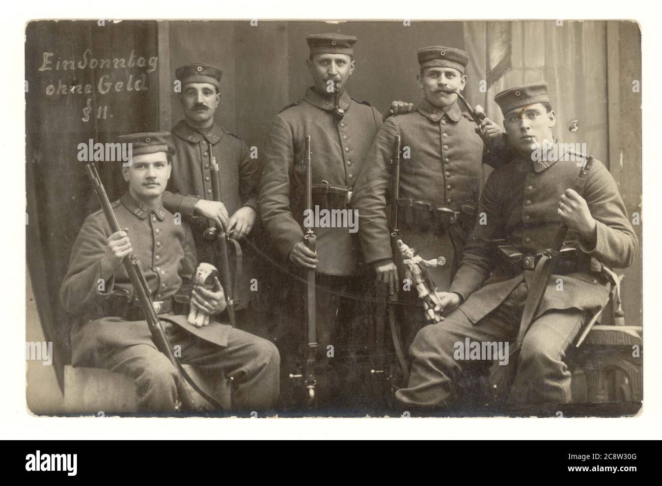 Carte postale de l'époque de la WW1 des soldats d'infanterie allemands avec des mascottes de jouet tenant des fusils, portant des casquettes de champ (kratzchen) - inscrit est "un dimanche sans argent", profitant d'un congé d'une journée ayant une photo prise avec des camarades, l'armée prussienne, éventuellement 7ème division, l'Empire allemand 1914-1918 Banque D'Images