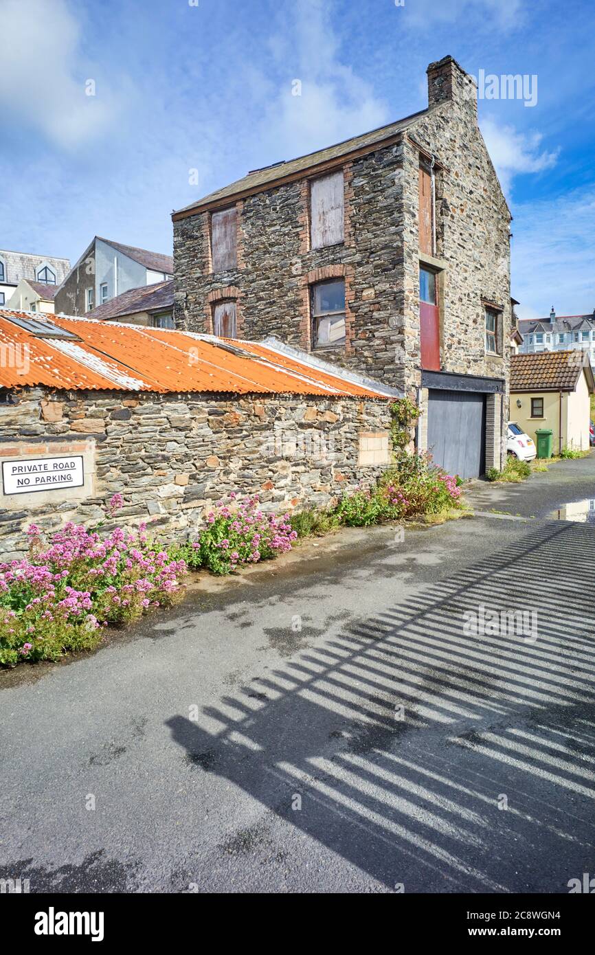 Un ancien entrepôt de stockage de constructeurs dans un état de déréparation et de dilapidation avec des fenêtres pourries et des trous dans les murs de pierre Banque D'Images