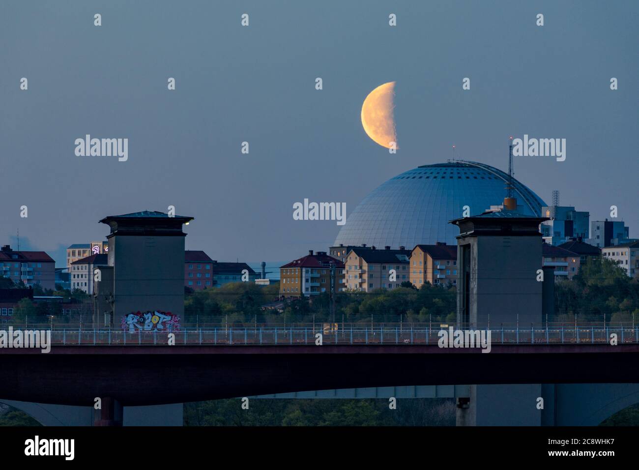 Stockholm, Suède la nuit, l'Ercisson Globe Arena avec une demi-lune qui s'élève sur le pont du train Arsta. | utilisation dans le monde entier Banque D'Images