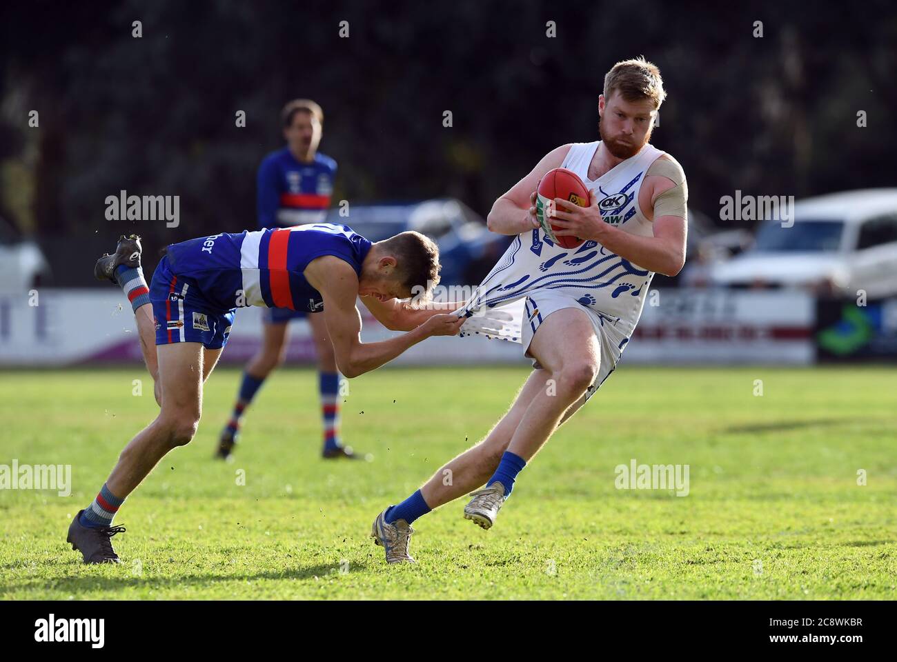 Un joueur de football de Tarrawingee est suspendu sur la chemise de son adversaire de Bright lors d'un match de football dans le nord-est de Victoria, en Australie Banque D'Images