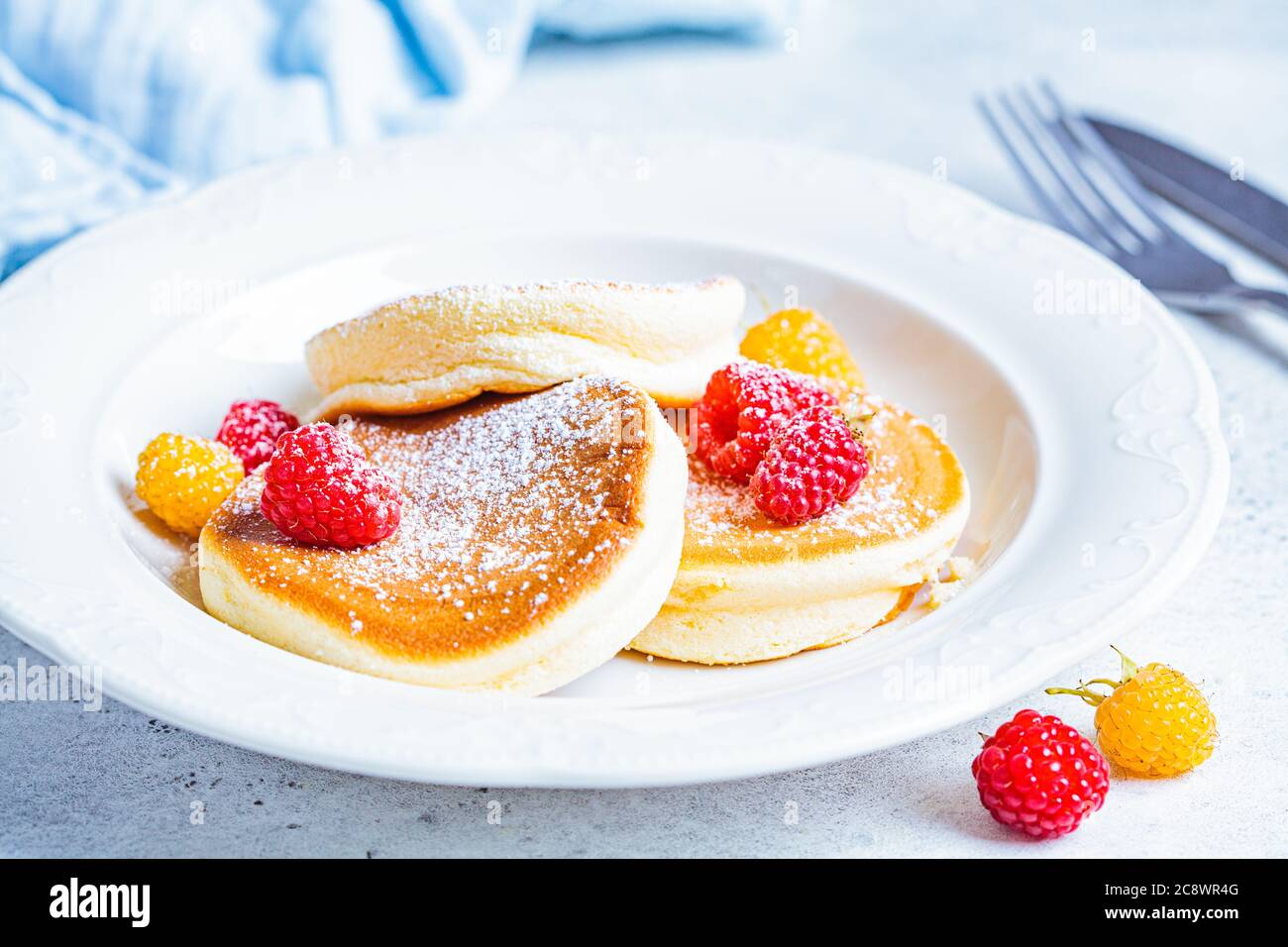Crêpes japonaises moelleuses aux framboises dans une assiette blanche, fond blanc. Concept de cuisine japonaise. Banque D'Images