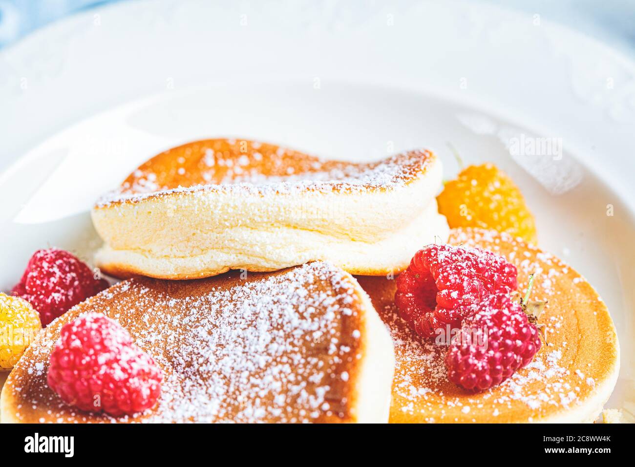 Crêpes japonaises moelleuses aux framboises dans une assiette blanche, fond blanc. Concept de cuisine japonaise. Banque D'Images