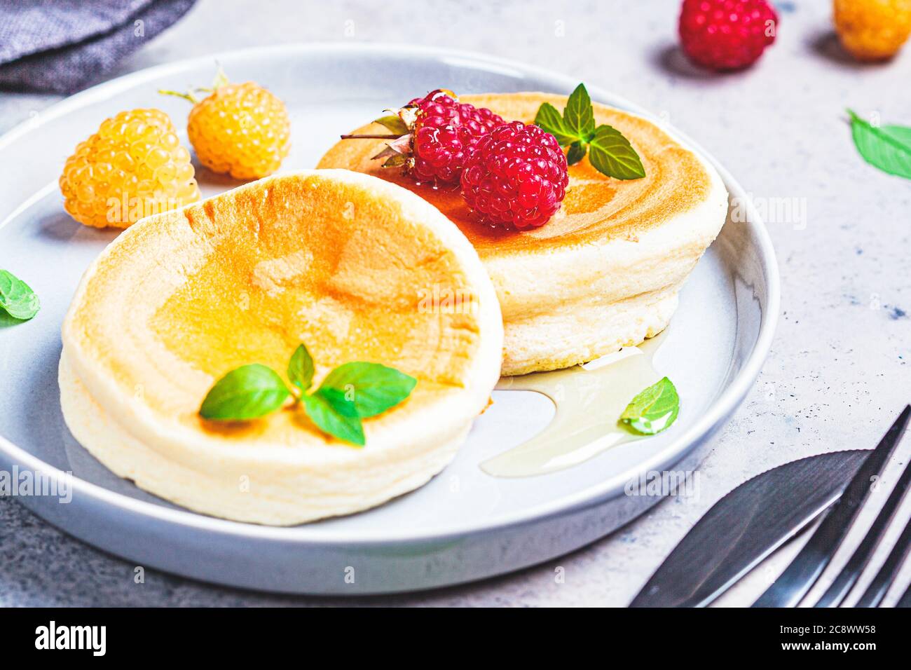 Crêpes japonaises moelleuses aux framboises dans une assiette grise, fond gris. Concept de cuisine japonaise. Banque D'Images