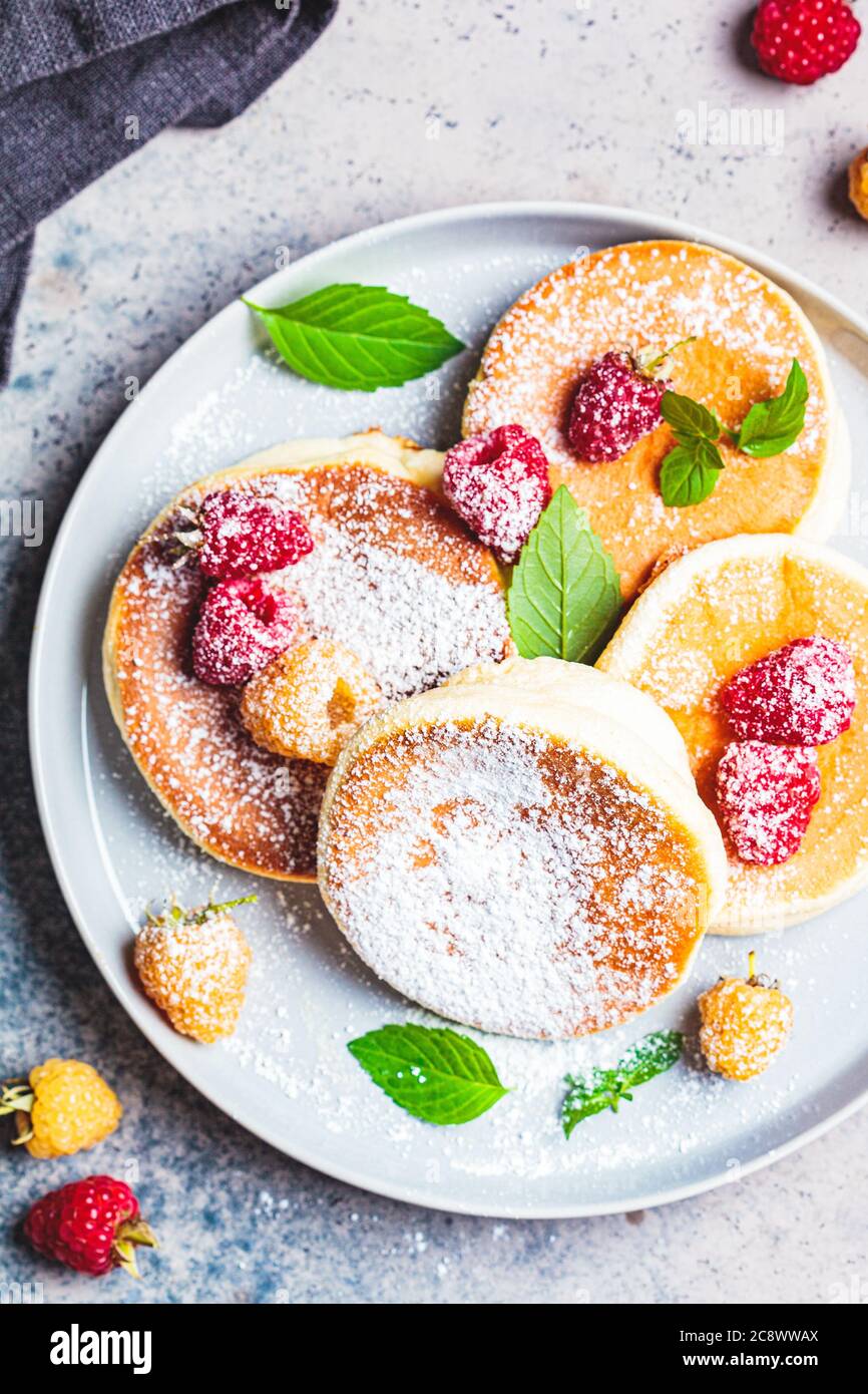 Crêpes japonaises moelleuses aux framboises dans une assiette grise, fond gris. Concept de cuisine japonaise. Banque D'Images