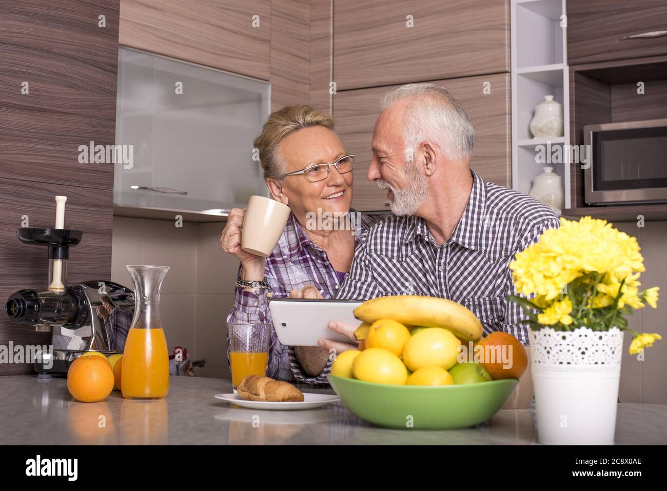 Heureux couple de personnes âgées de race blanche debout derrière le comptoir de la cuisine Banque D'Images