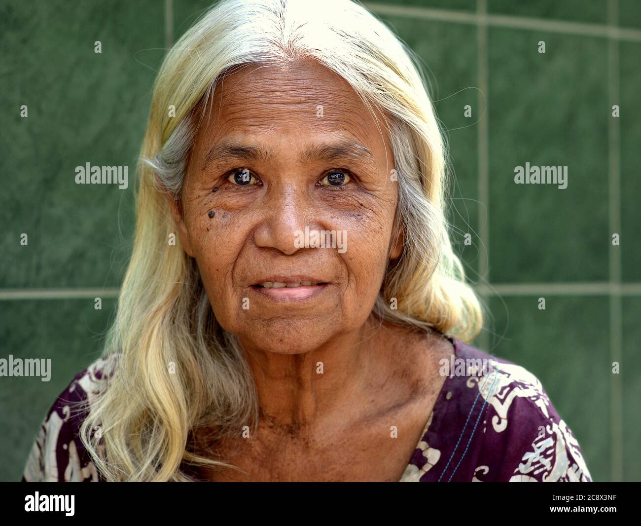 Femme birmane âgée avec de beaux cheveux longs pose pour la caméra. Banque D'Images