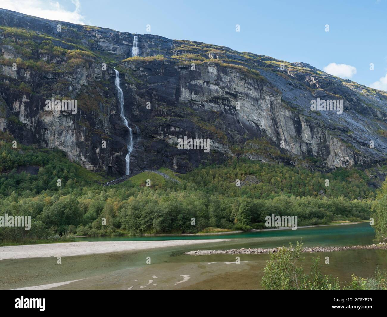 Grande cascade avec rivière turquoise Rauma dans la vallée de Romsdalen avec des rochers et une forêt verte. Bleu ciel blanc nuages arrière-plan. Paysage d'été de Norvège Banque D'Images