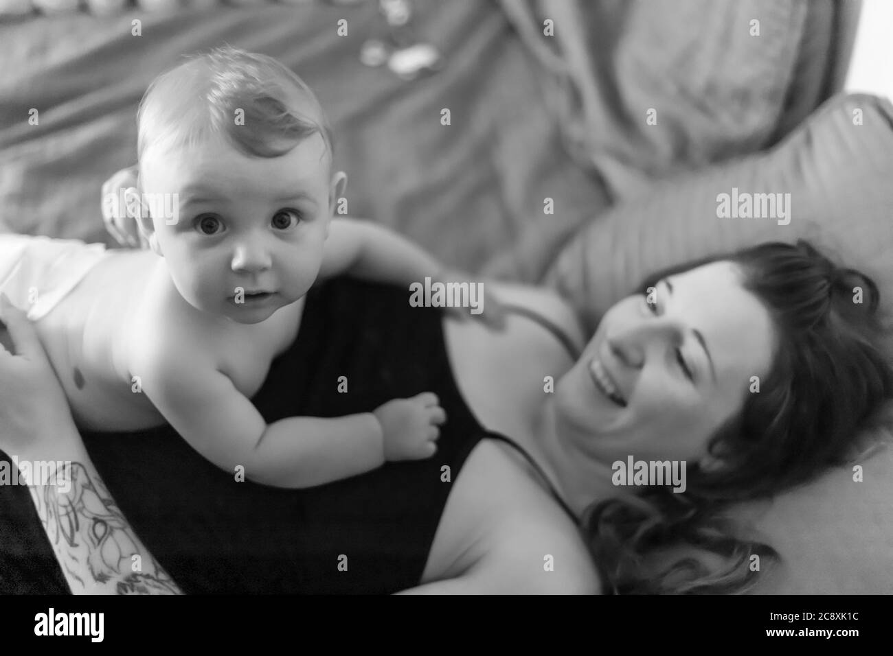 Mere Et Bebe Fils Joyeuse Intimite Bebe Allonge Sur La Poitrine De Sa Mere Et Regardant La Camera Avec Une Expression Drole Et Surprise Noir Et Blanc Pic Photo Stock Alamy
