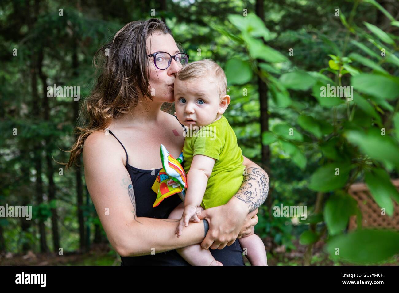 Portrait D Une Mere Et De Son Bebe A L Exterieur Dans Les Bois Maman Tient Son Fils Dans Ses Bras Et Embrasse Sa Tete Bebe Regardant L Appareil Photo Photo Stock Alamy