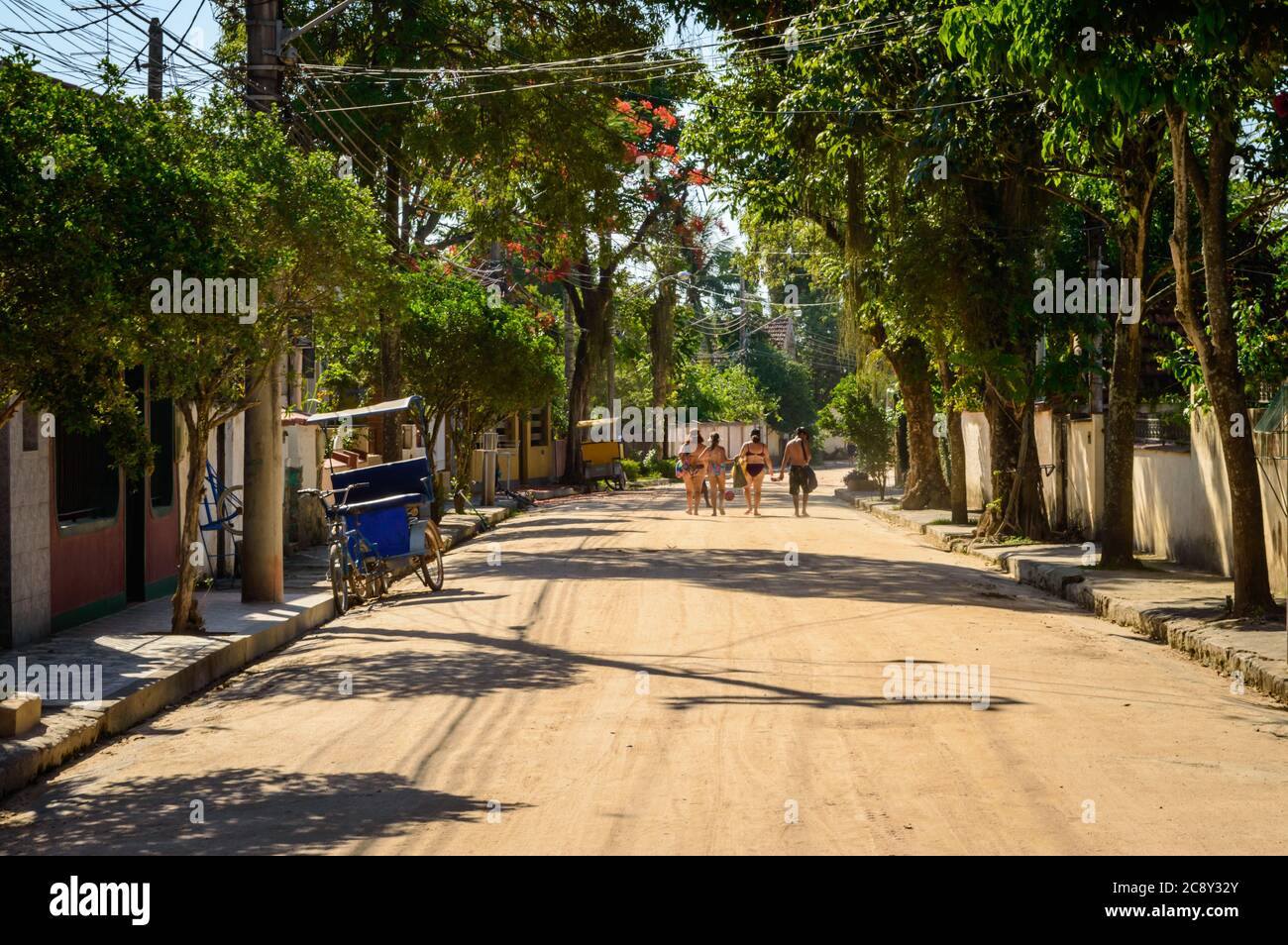 Les amateurs de plage de l'île de Paquetá se promeutrent sur une route de terre tranquille dans leurs maillots de bain. Banque D'Images