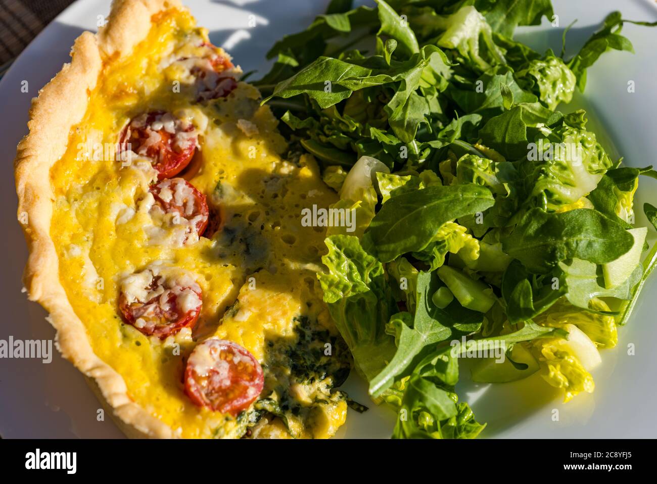 Table extérieure avec repas d'été de tomate, d'épinards et d'oeuf quiche Lorraine et salade verte Banque D'Images