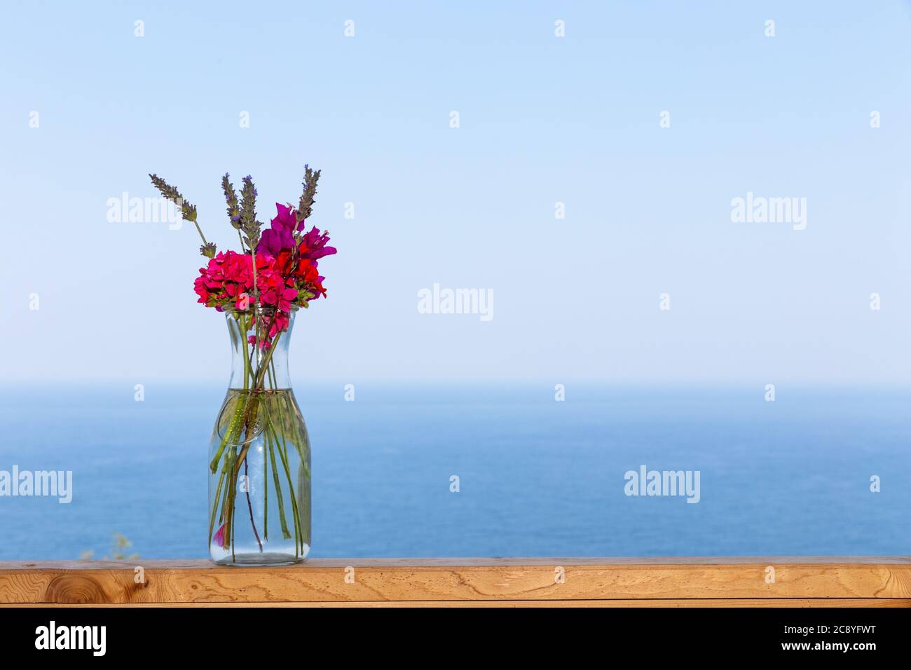 Beau bouquet dans vase sur main rail en bois sur fond de paysage marin Banque D'Images