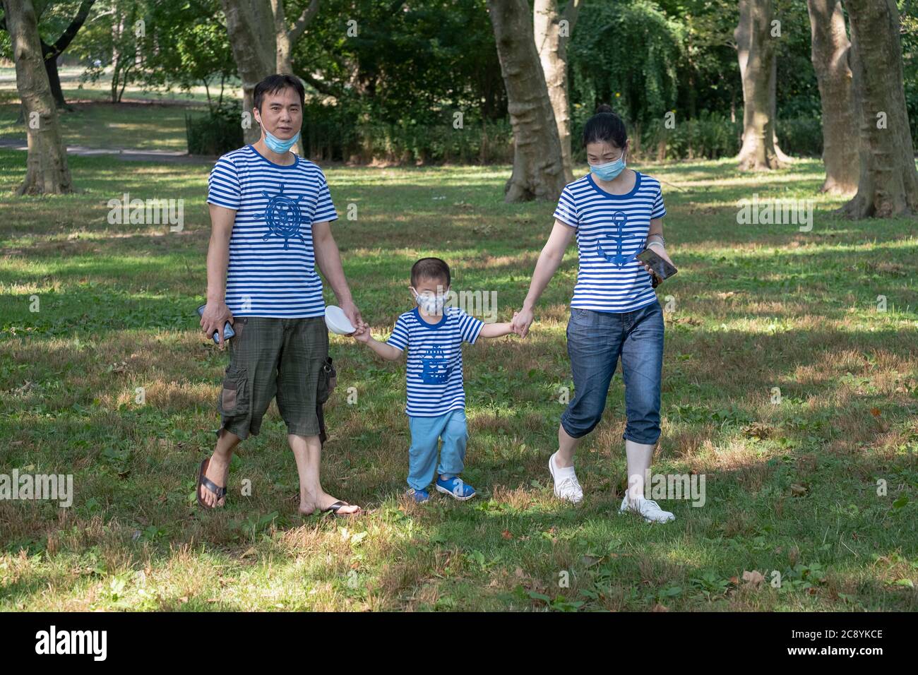 Une famille qui marche dans le parc avec des vêtements assortis. À Flushing, Queens, New York. Banque D'Images