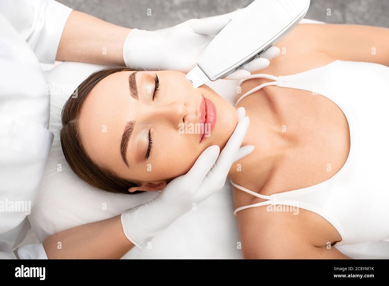Une femme qui obtient la peau de peau ultrasonique, une procédure de nettoyage à l'aide d'un dispositif spécial. Procédure de décollement par ultrasons et de nettoyage en gros plan de la face Banque D'Images