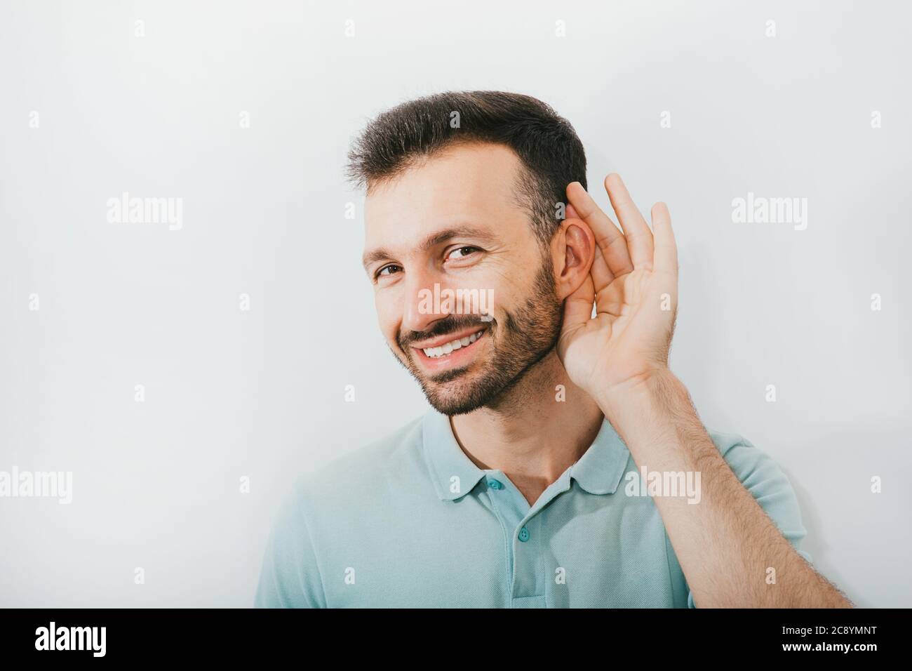 Vérifiez votre audition. L'homme positif tient sa main près de son oreille, sur un fond gris. Santé de l'oreille, traitement et diagnostic de l'audition Banque D'Images