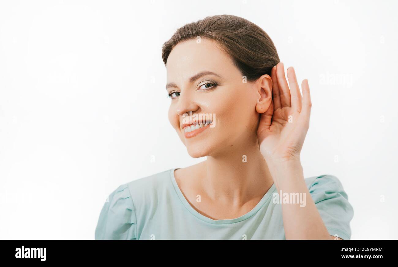 Vérifiez votre audition. Une femme caucasienne positive tient la main près de l'oreille, isolée sur fond blanc. Santé de l'oreille, traitement, et diagnostic de l'audition Banque D'Images