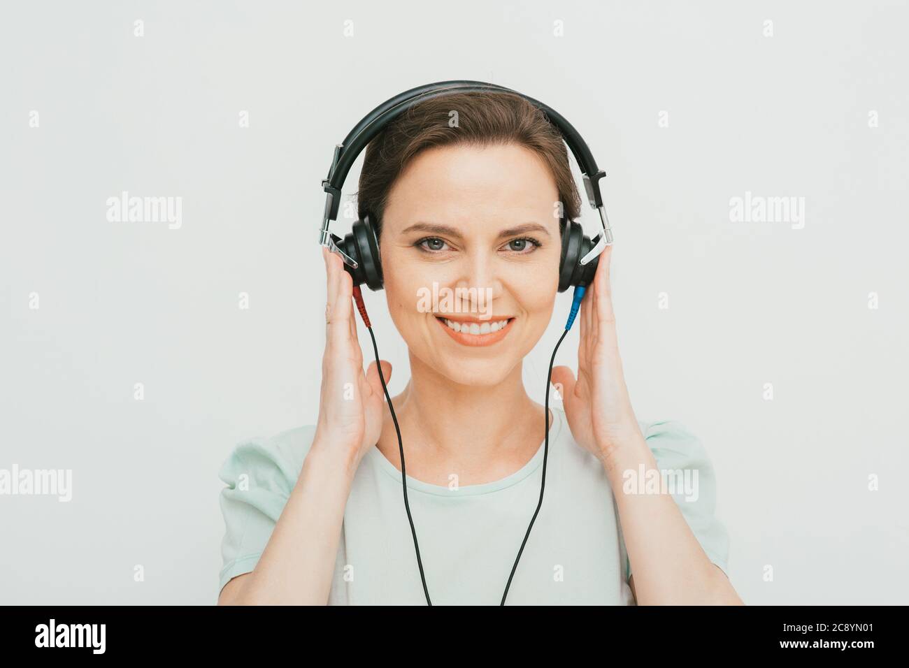 Test auditif, diagnostic auditif. Une femme portant un casque ayant un test d'audiométrie isolé en blanc Banque D'Images