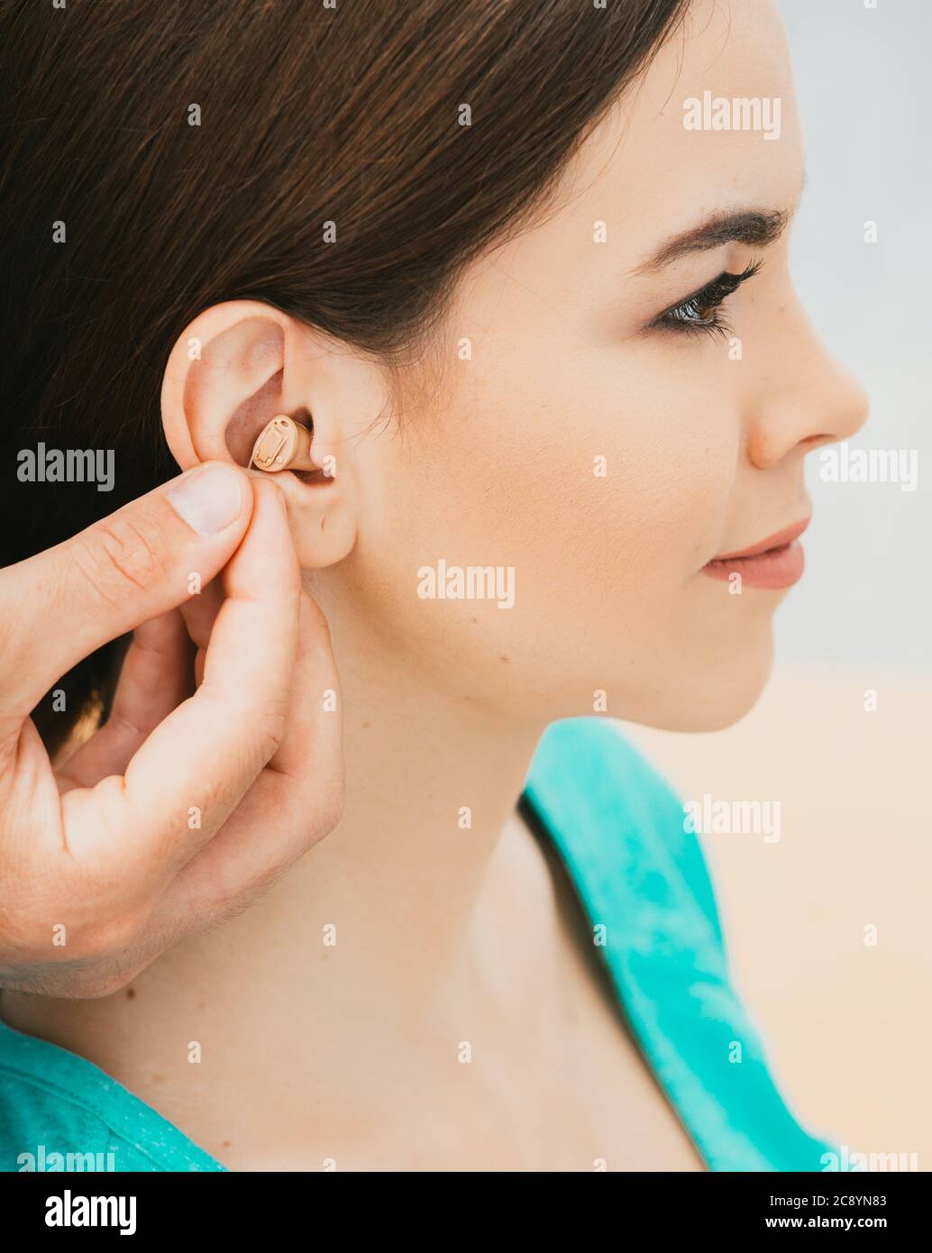 Jeune patient avec prothèse auditive intra-auriculaire, gros plan sur l'oreille féminine. La solution auditive, l'audiologiste insérant une prothèse auditive Banque D'Images