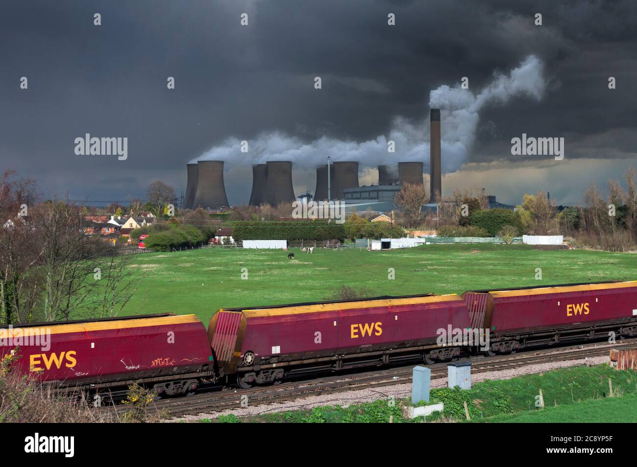 EWS Merry Go Round train charbon HTA wagons passant par la centrale électrique d'Eggborough avec un ciel noir sombre de tempête et de la vapeur des tours de refroidissement. Banque D'Images