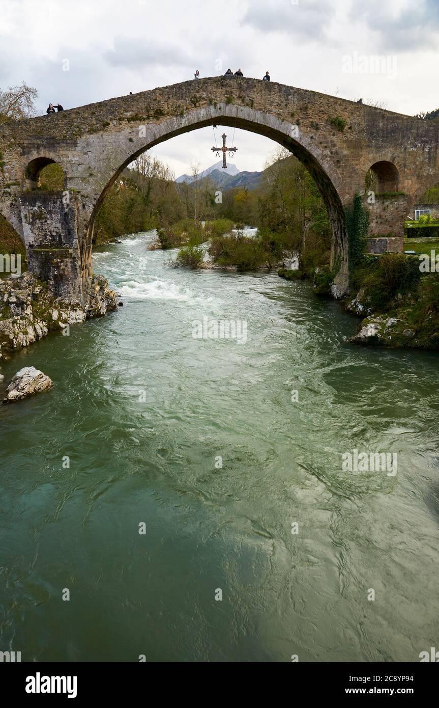 Touristes sur le pont romain mal appelé avec sa Cruz de la Croix de Victoria accrochant de lui sur la rivière Sella (Cangas de Onís, Asturias, Espagne) Banque D'Images