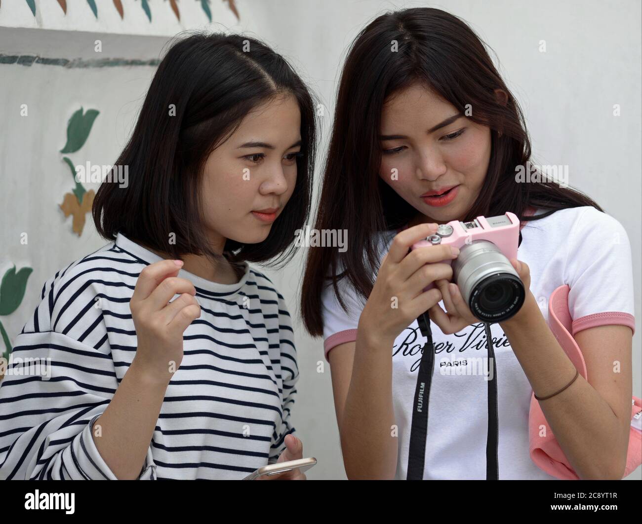 Deux jolies filles thaïlandaises regardent leur wefie sur l'écran LCD d'un appareil photo numérique sans miroir. Banque D'Images