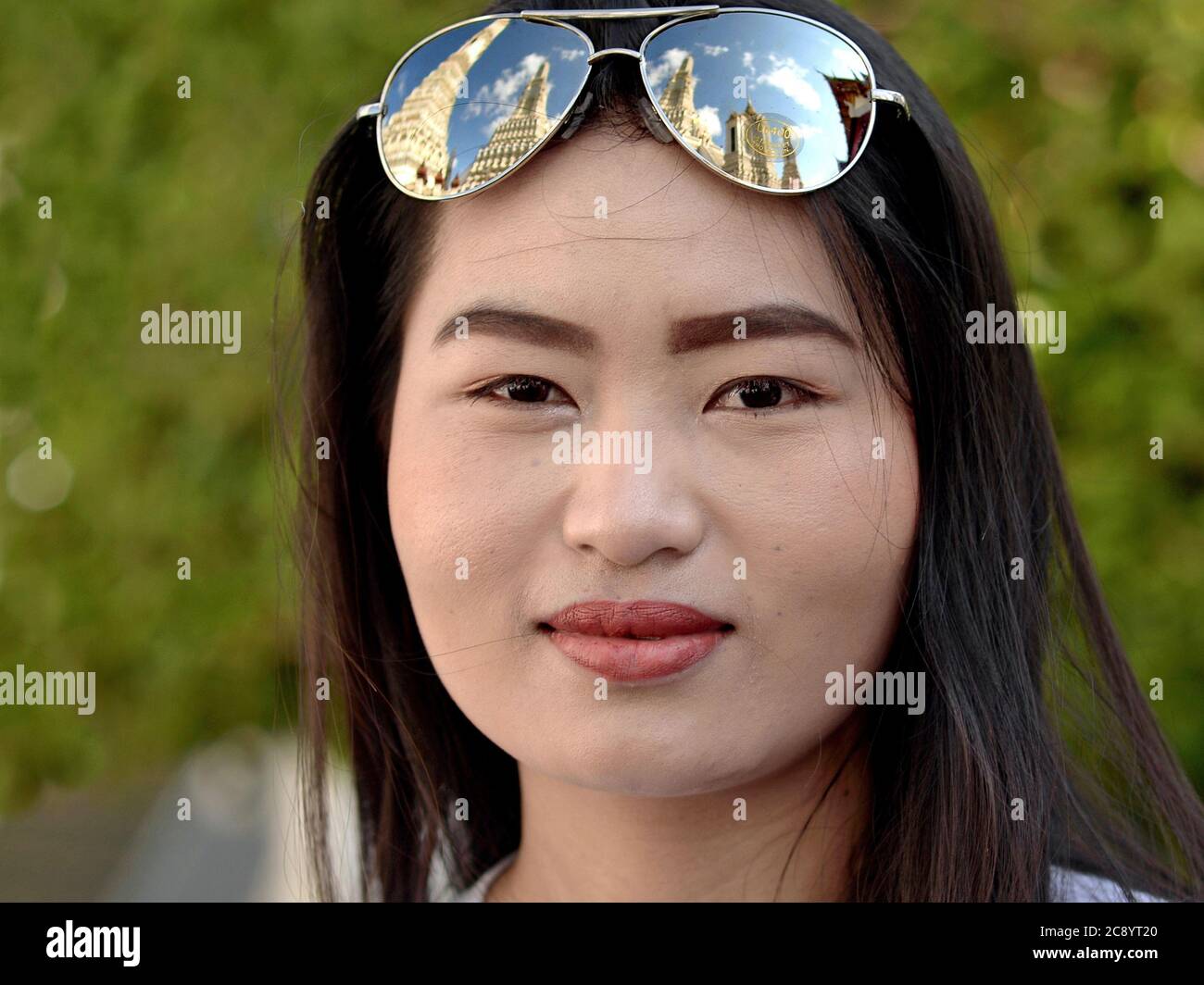 Une jeune touriste asiatique porte des lunettes de soleil en miroir (avec  le reflet du Wat Arun de Bangkok) sur le dessus de sa tête et pose pour la  caméra Photo Stock -