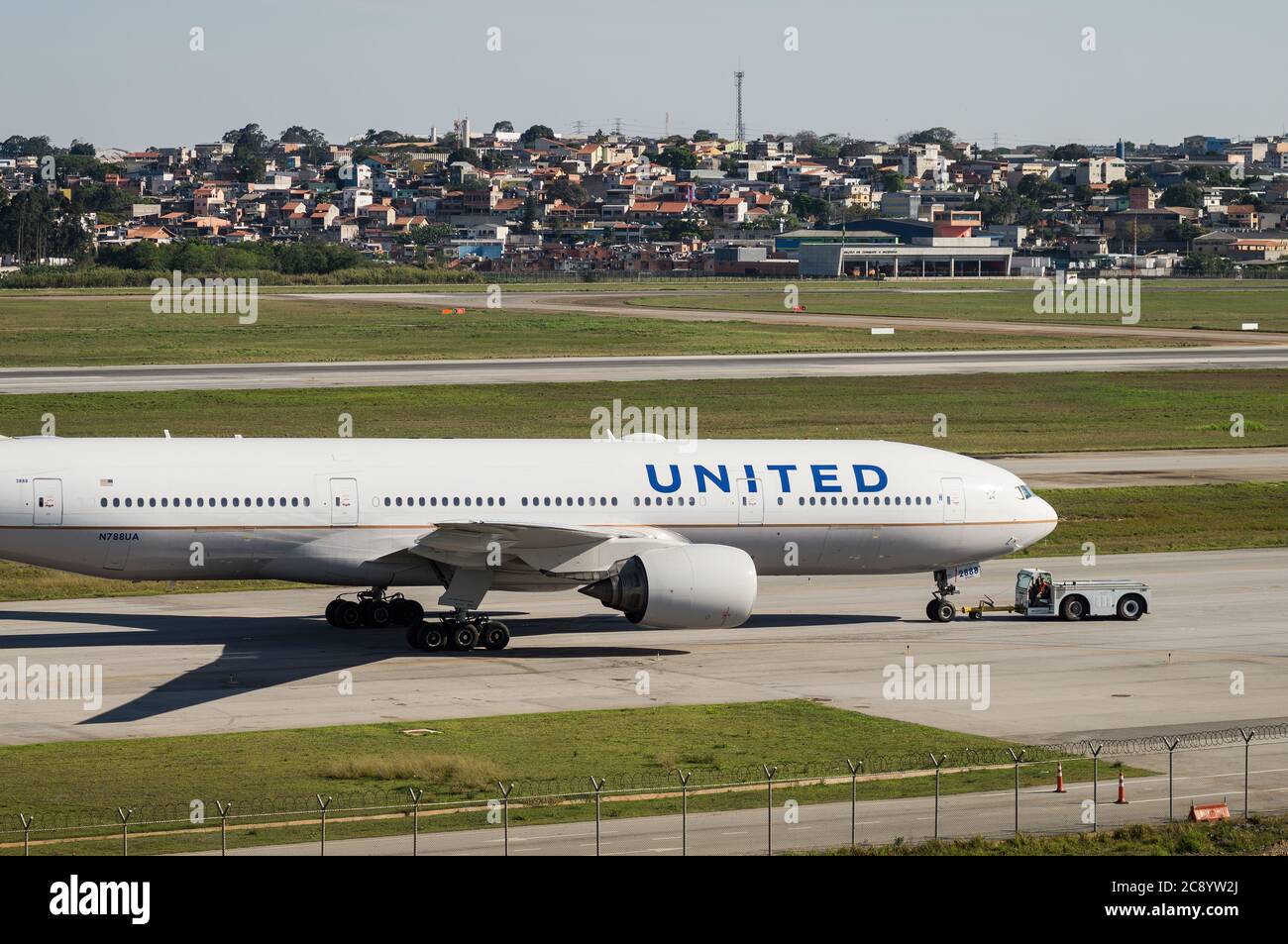 Un Boeing 777-222ER (Reg N788UA) est poussé par un tracteur de refoulement sur l'un des taxis de Sao Paulo/Guarulhos Intl. Aéroport avant le départ. Banque D'Images