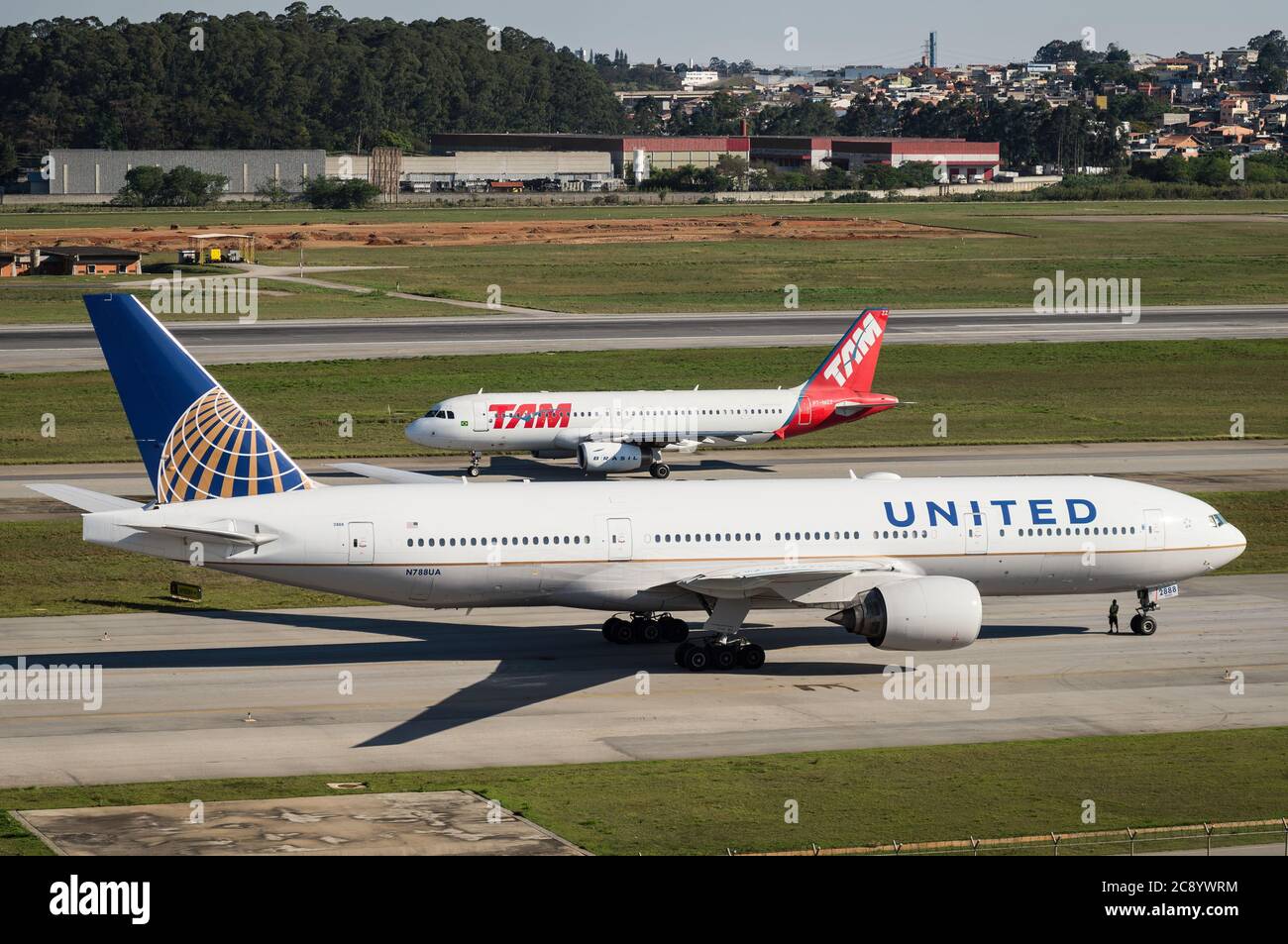 Boeing 777-222ER (Reg N788UA) se préparant à partir sur l'un des taxis tandis qu'un Airbus A320 passe à proximité de l'aéroport international de Sao Paulo/Guarulhos Banque D'Images