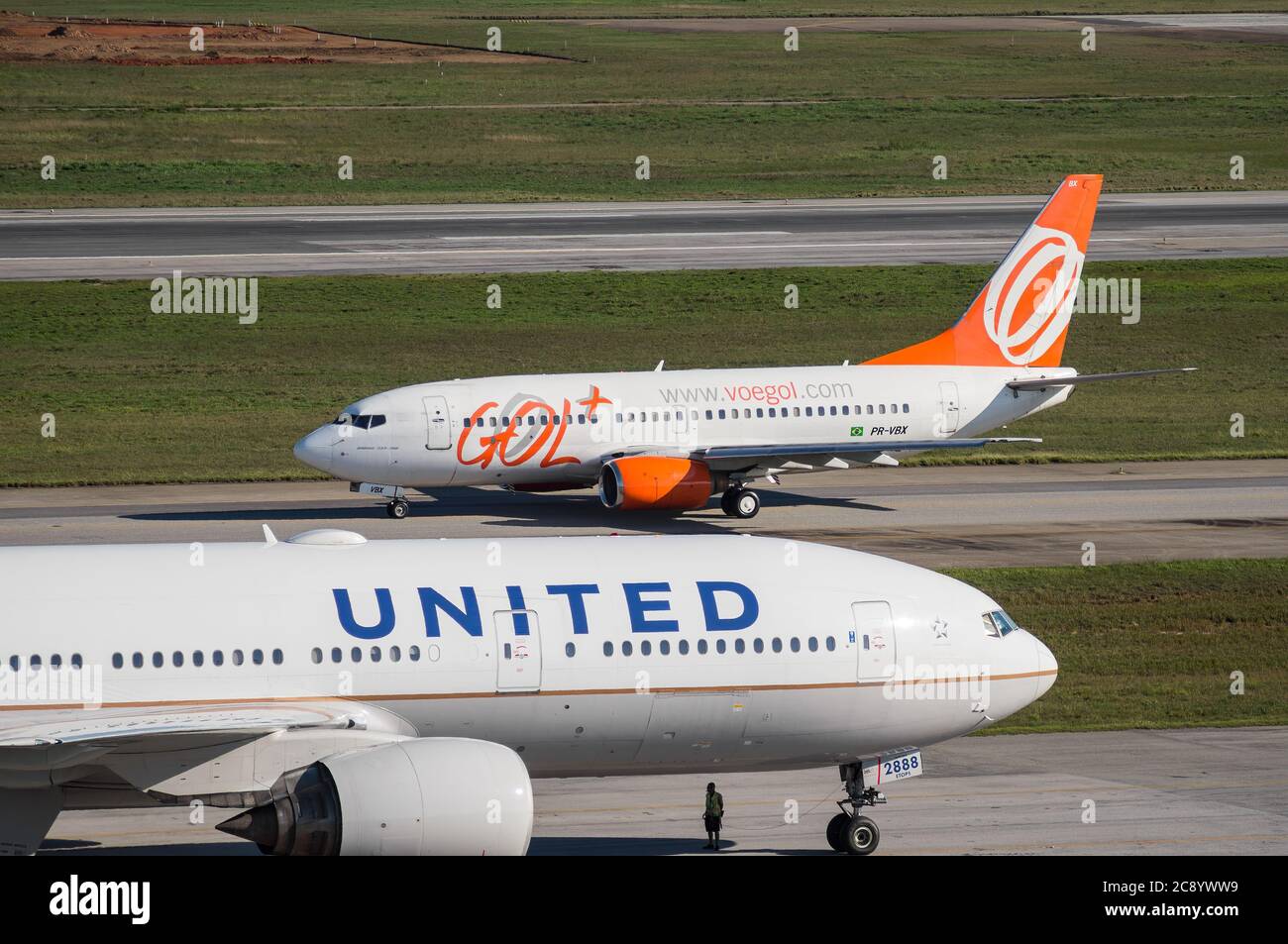 Compagnies aériennes GeD Boeing 737-700NG (PR-VBX - Old Livery) taxant la piste 27R alors qu'il passe par un Boeing 777 à l'aéroport international de Sao Paulo/Guarulhos. Aéroport. Banque D'Images