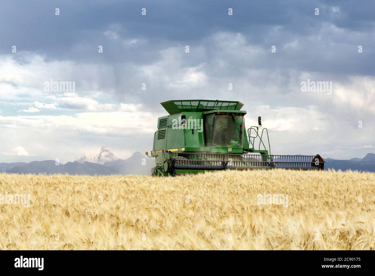 Machines agricoles récoltant du blé dans les champs fertiles de l'Idaho, avec la chaîne de Teton Mountain en arrière-plan. Banque D'Images