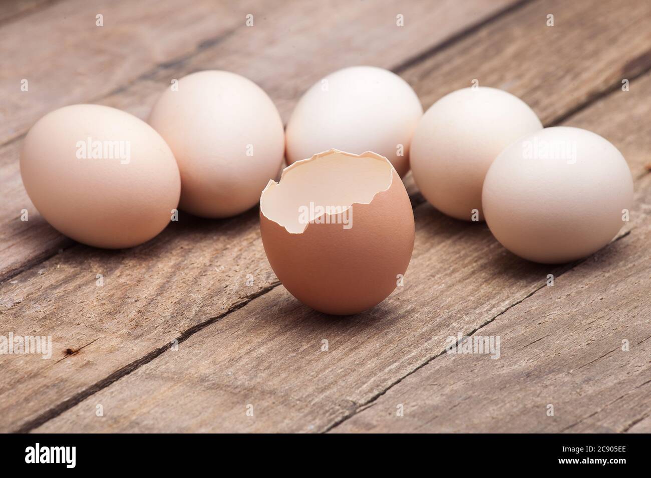 Les oeufs qui sont disposés sur une table en bois de vieilles planches avec l'oeuf cassé au premier plan, personne. Banque D'Images