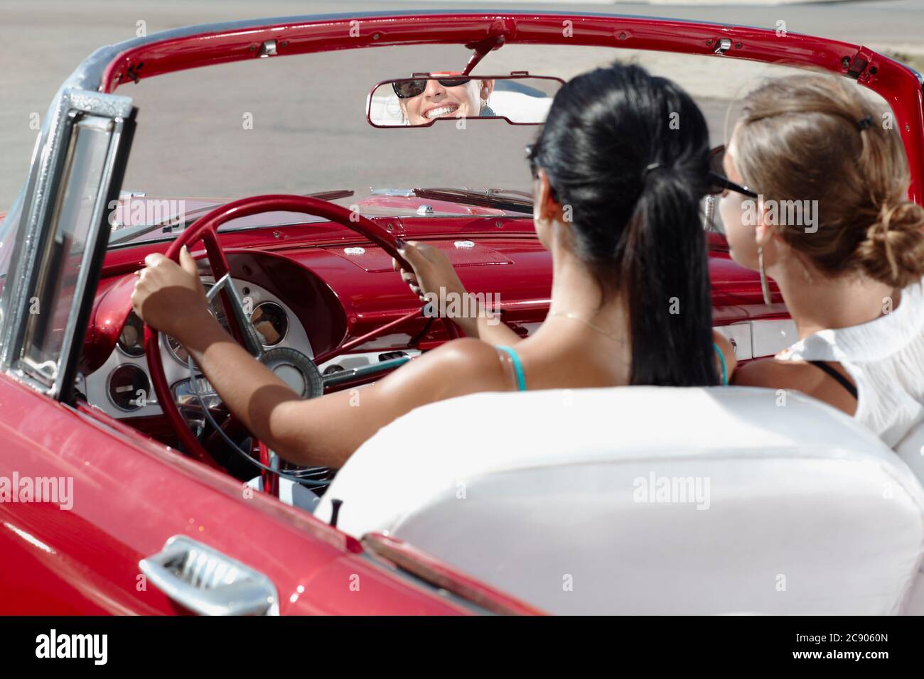 Les femmes heureuses conduisent une voiture convertible louée pour des vacances Banque D'Images