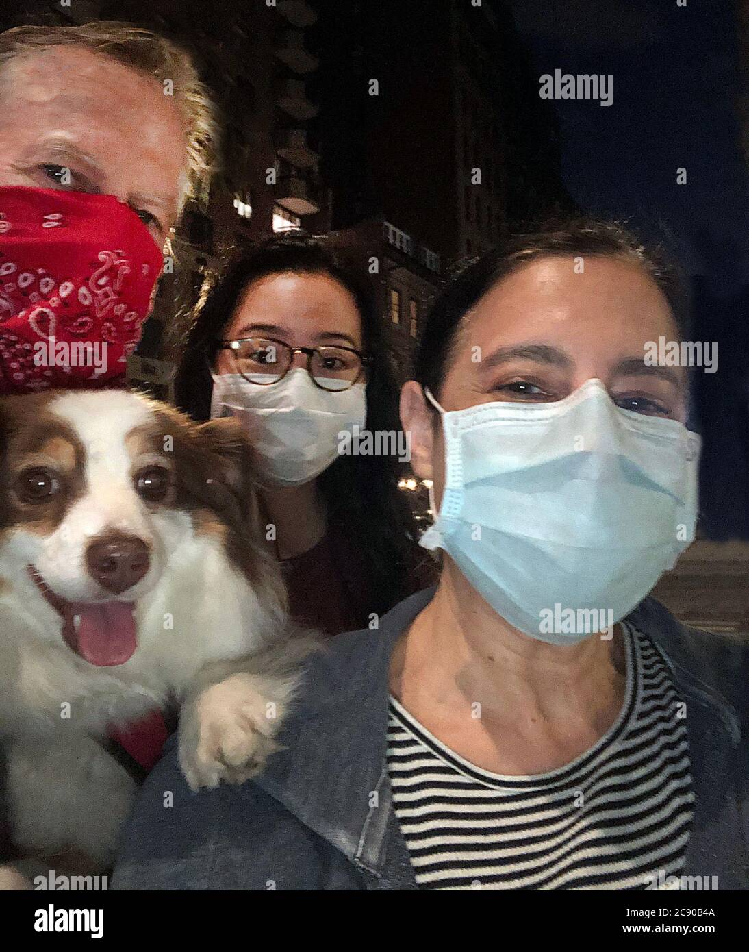 Tête et épaules Portrait de famille avec un chien portant des masques protecteurs la nuit, New York, New York, Etats-Unis Banque D'Images