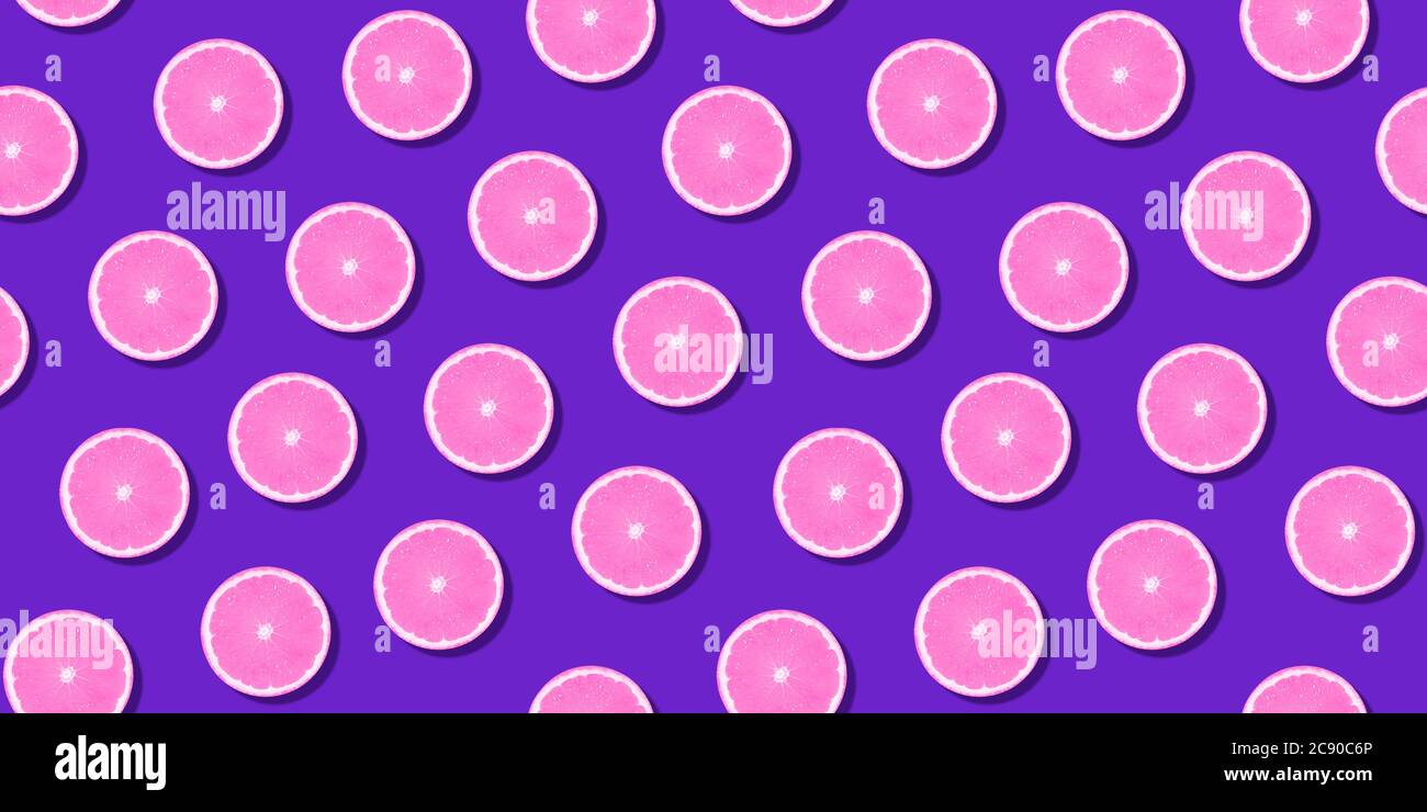Motif sans couture rose agrumes orange citron couché sur une surface violette. Papier peint en tranches d'agrumes frais et coloré. Des couleurs éclatantes et créatives, l'été Banque D'Images