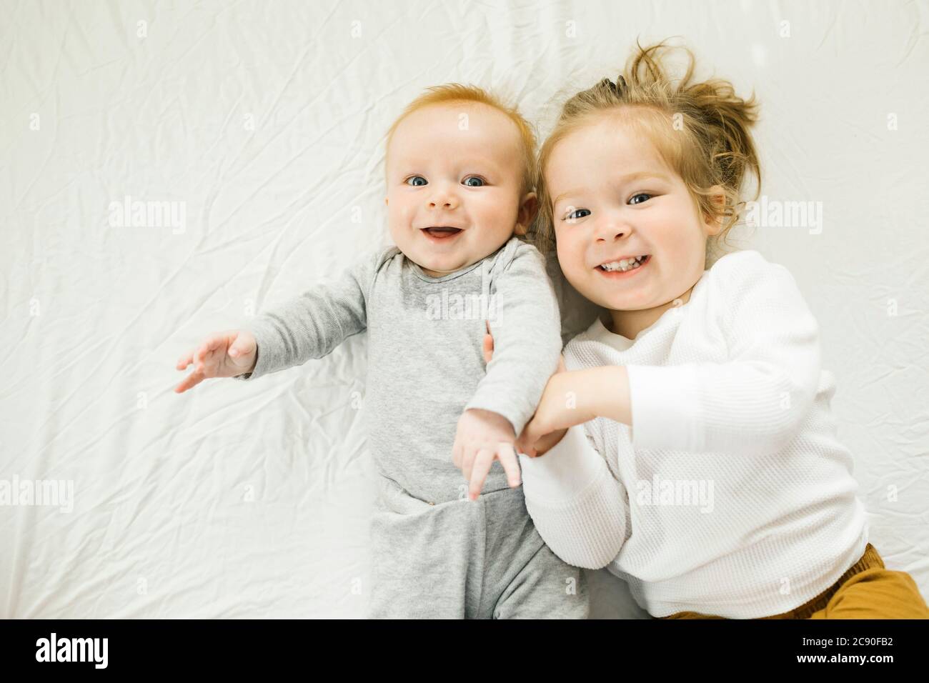 Portrait de frères et sœurs souriants allongé sur le lit Banque D'Images