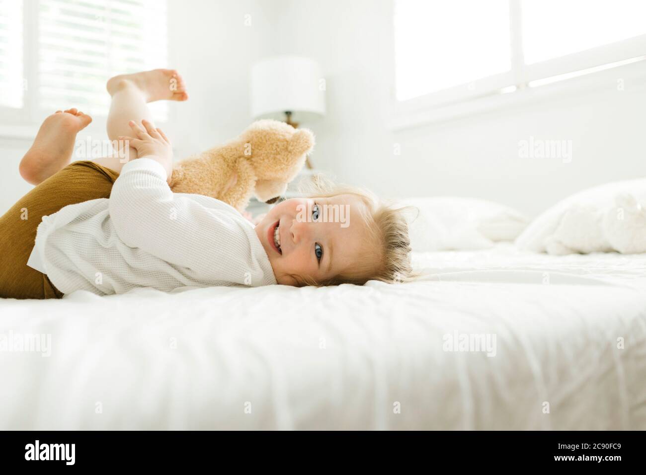 Petite fille couchée au lit avec son jouet ours en peluche Banque D'Images