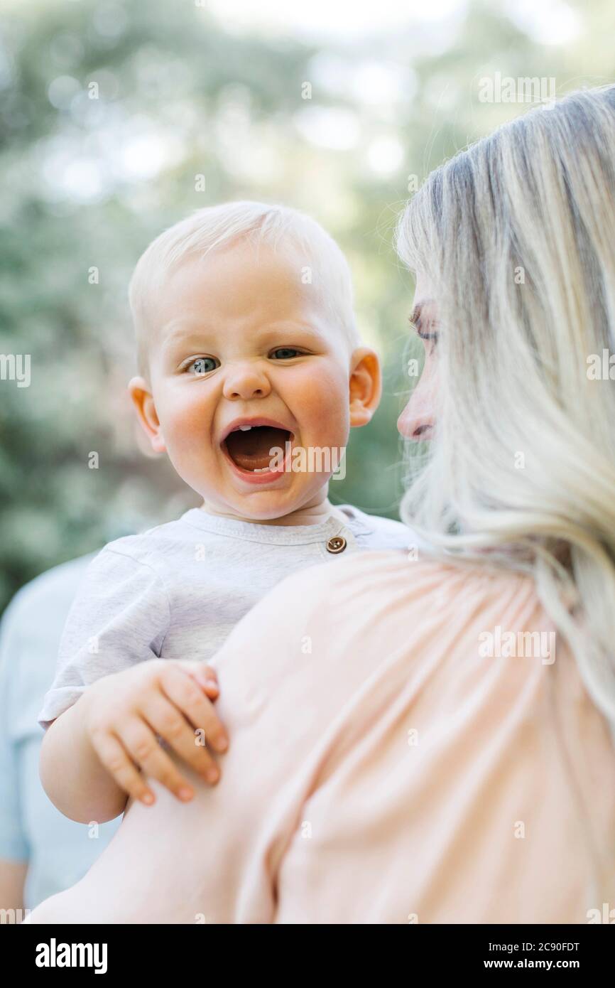 Bébé garçon riant dans les bras des mères Banque D'Images